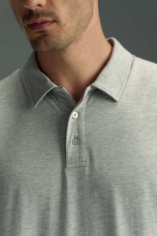 A man wears a WearEver Outbound Polo—light grey, breathable cotton-blend with a collar and three buttons—shown from shoulders to just above the chest against a plain grey background.