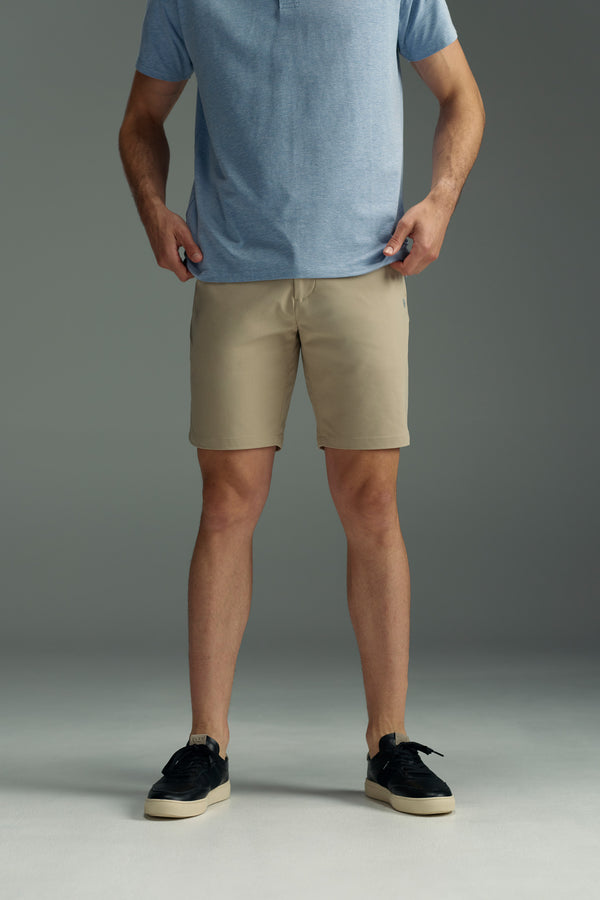 A person wearing a light blue short-sleeve shirt, black sneakers, and WearEver Switch Short by WearEver stands on a gray floor, holding the sides of their shorts. The image is cropped at the shoulders.