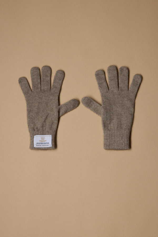 A pair of gray NZ Made Perino Gloves by Woolyarns Perino lies flat on a beige surface, crafted from luxurious merino possum silk. The left glove features a white wrist label, emphasizing these premium New Zealand accessories.