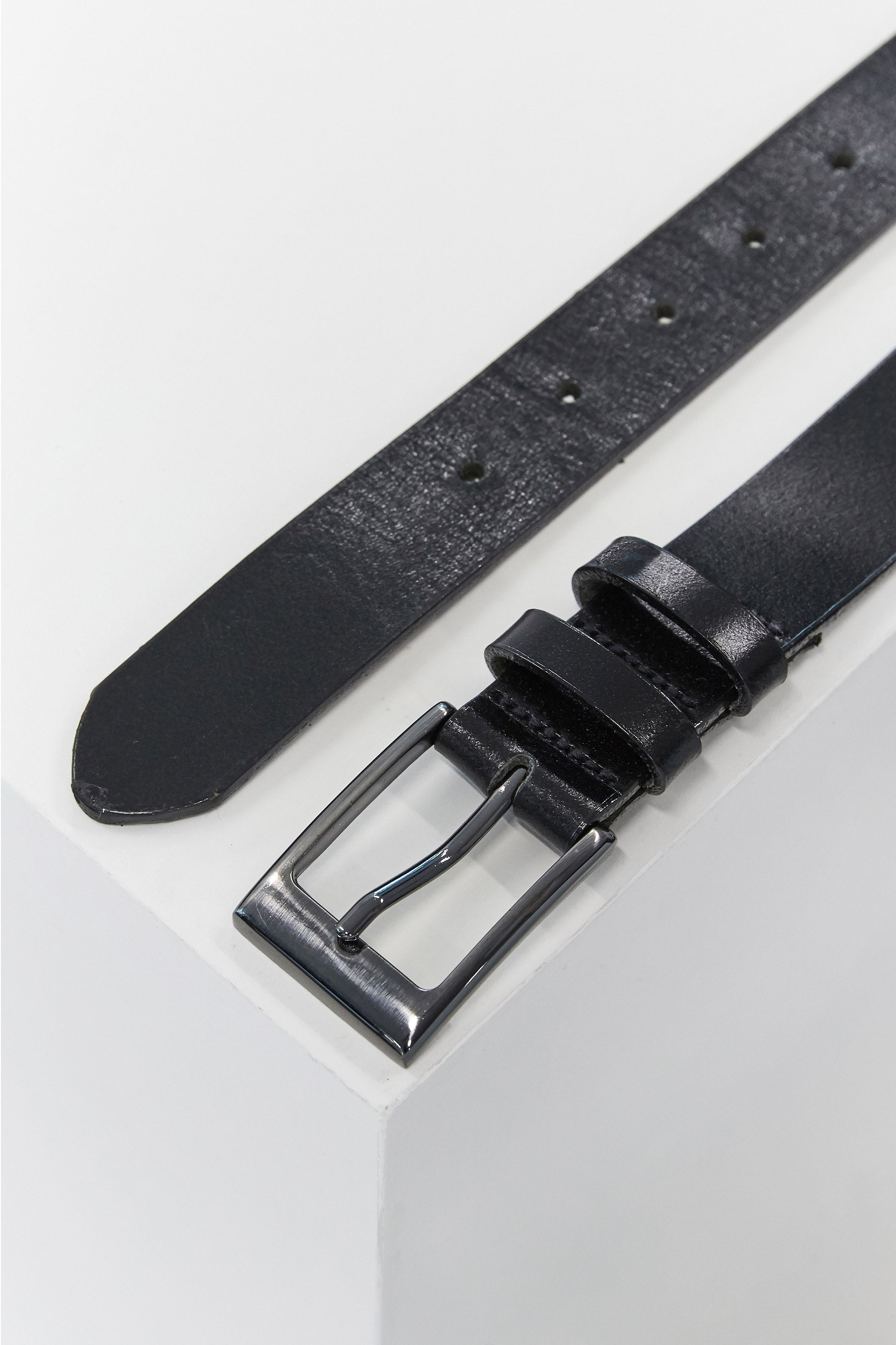 A close-up of the Frances Leather Belt by Barkers, featuring black leather and a silver square buckle, partially unbuckled on a white surface—crafted in New Zealand for timeless style.