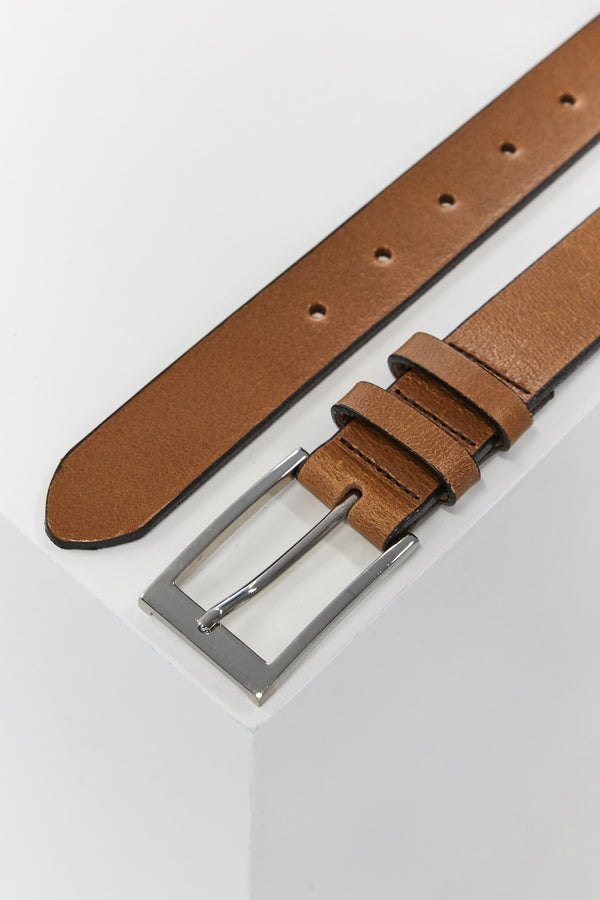 The Frances Leather Belt by Barkers, featuring brown leather and a silver square buckle, is partially rolled with the pointed end extended on a white surface.