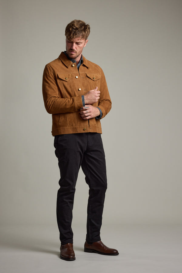 Man in Barkers Jackson Suede Trucker, black pants, and brown shoes on a plain background.