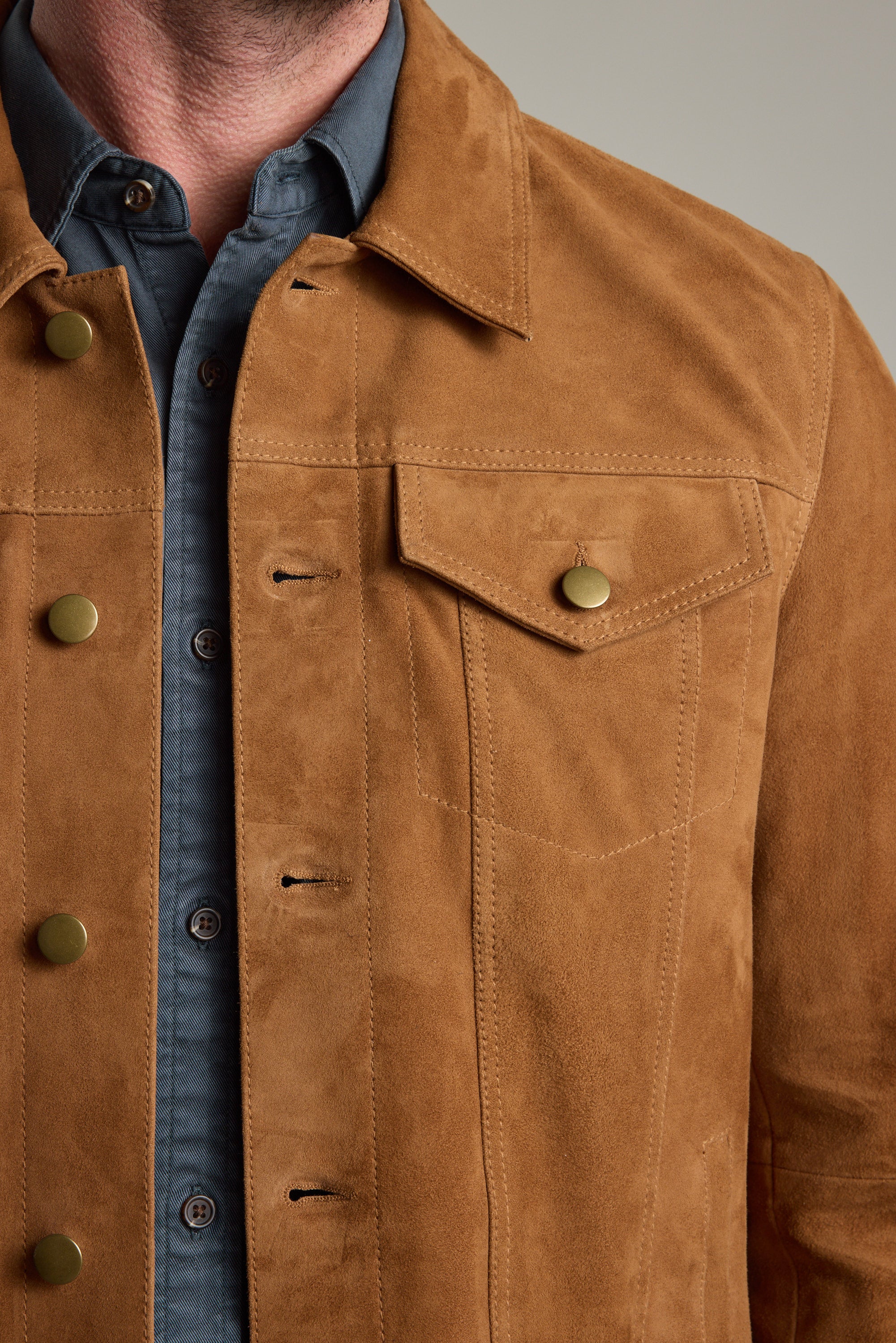 Man wears Barkers Jackson Suede Trucker over a blue button-up, shown neck to waist.