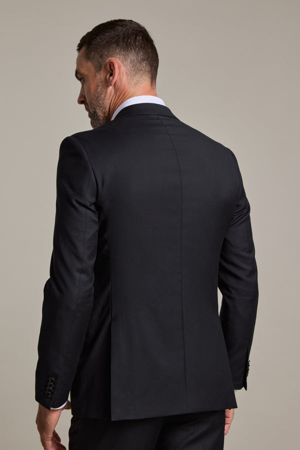 A man wearing the Barkers Mayfair ZQrx Suit Jacket in black over a white dress shirt is shown from the back, looking to his left against a plain light gray background.
