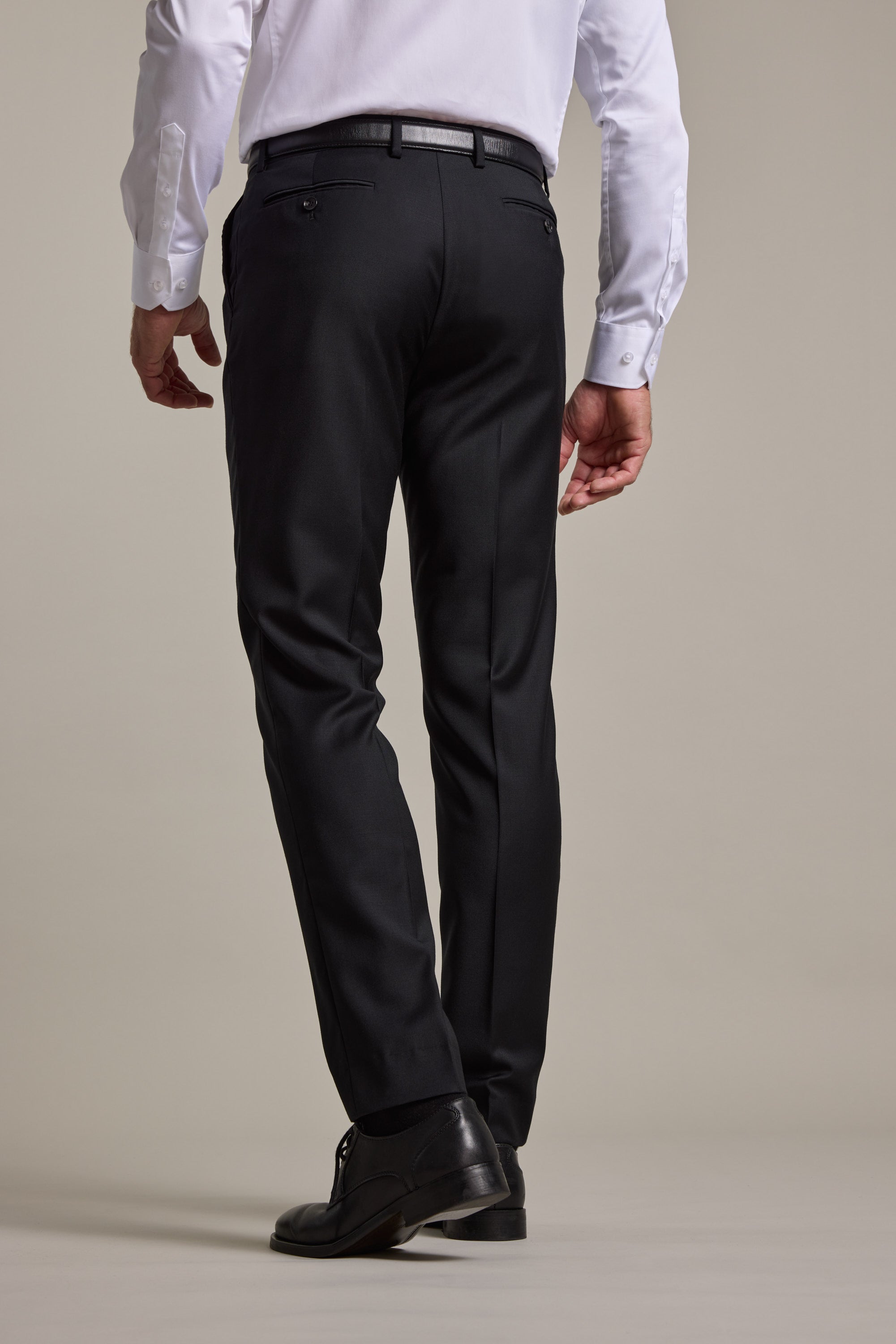 A man is shown from the back, standing against a plain light background, wearing Barkers' Mayfair ZQrx Suit Trouser and black shoes crafted from ethical merino.
