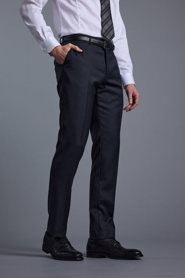 Wearing Barkers' Mayfair ZQ Suit Trouser, a white dress shirt, striped tie, black belt, and black dress shoes, a person stands with one hand in their pocket against a gray background.