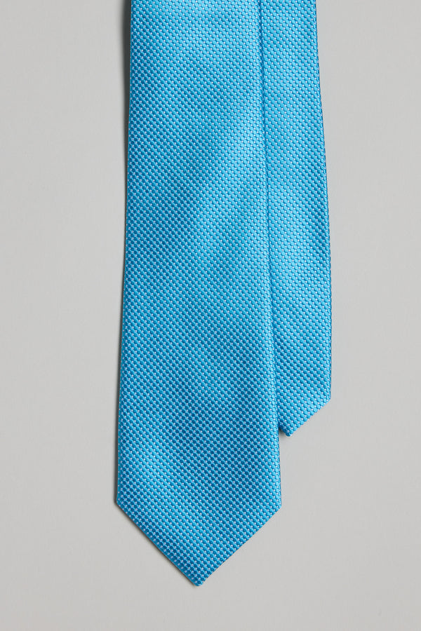 A close-up of the Eldert Texture Tie by Barkers—a bright turquoise blue silk necktie with a pointed tip—displayed against a plain light gray background.