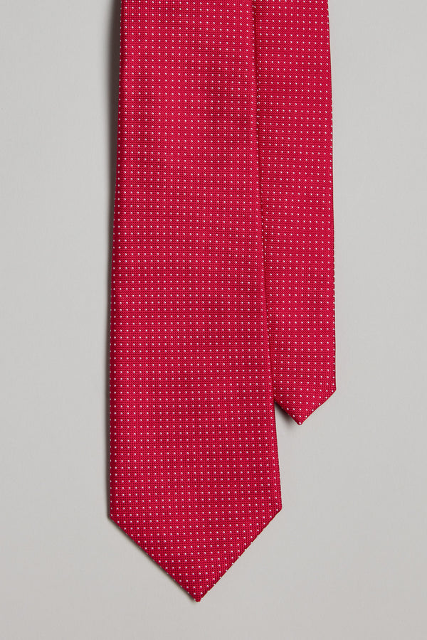 The Barkers Farry Pindot Tie, featuring a red base with tiny white dots, is displayed on a light gray background. Neatly arranged with the pointed end down, it's perfect for pairing with pocket squares or other silk accessories.