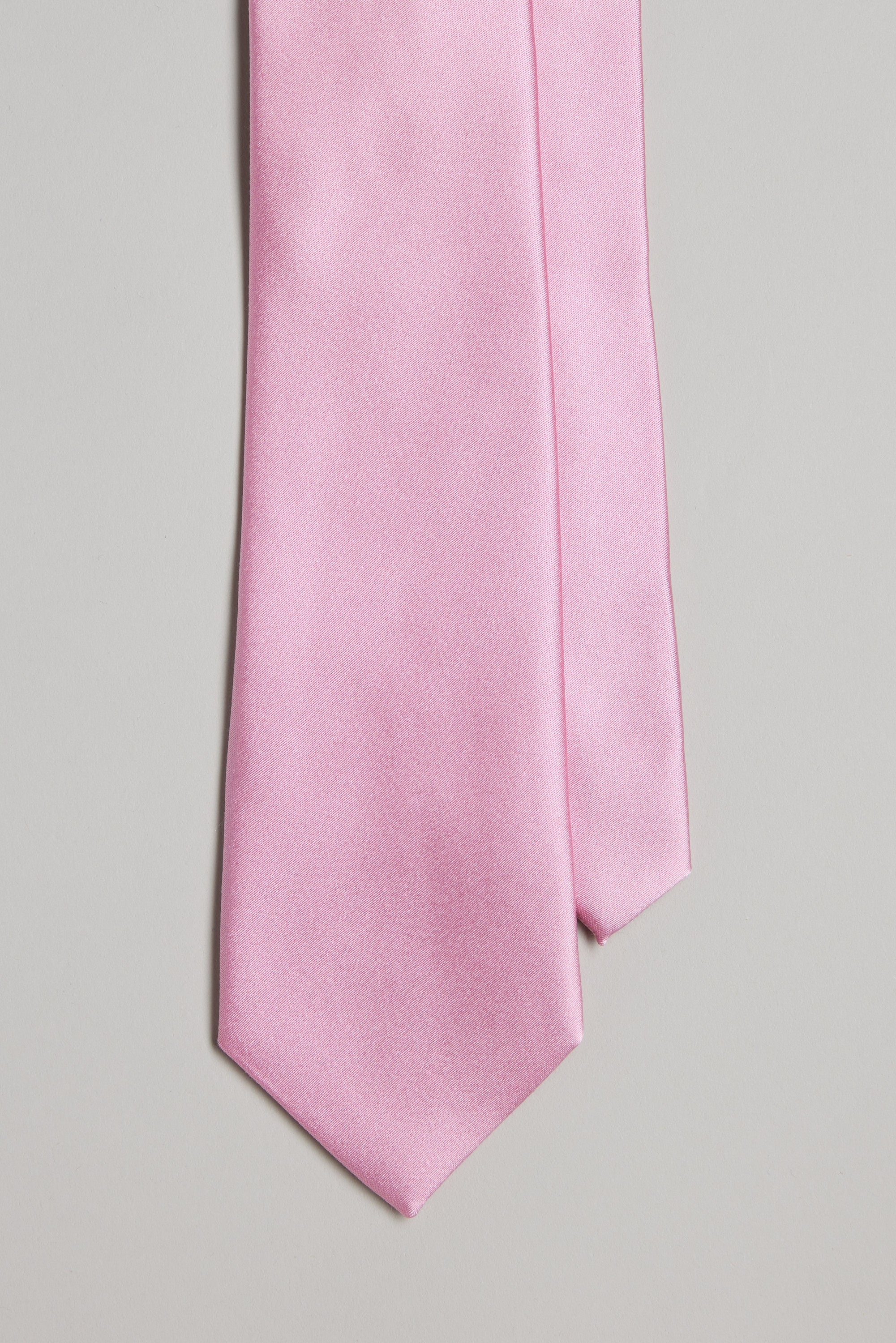 A close-up of the Cumberland Tie by Barkers, a light pink silk necktie, showcased against a plain light gray background.