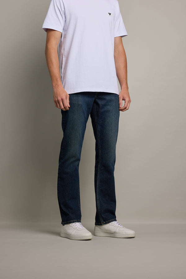 A person stands against a plain background, wearing a white t-shirt, Barkers Wanderer Denim Straight Jeans, and white sneakers. Their head is not visible in the image.