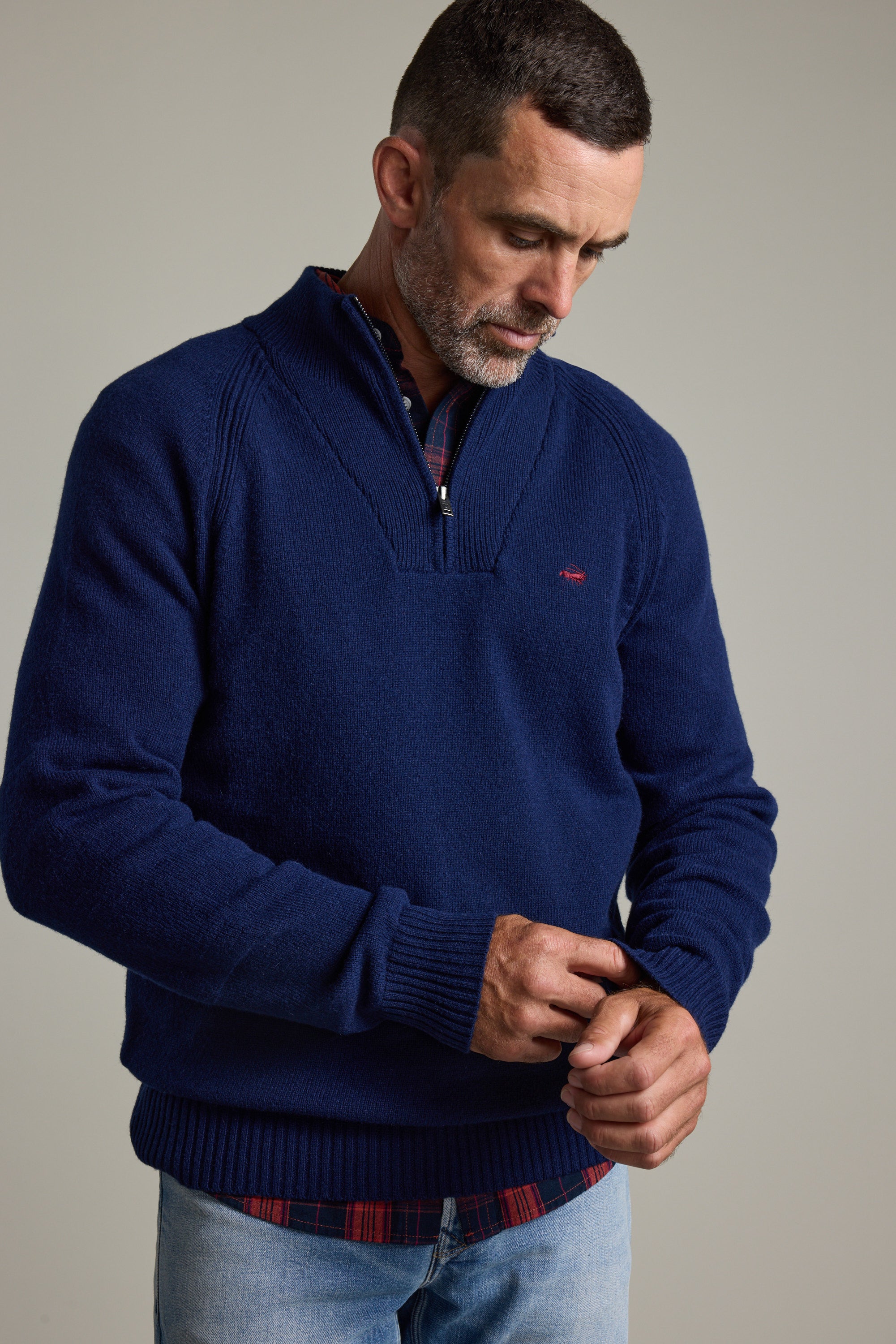 Man in Barkers Rowley Woollen 1/4 Zip and plaid shirt looks down, adjusting his sleeve.