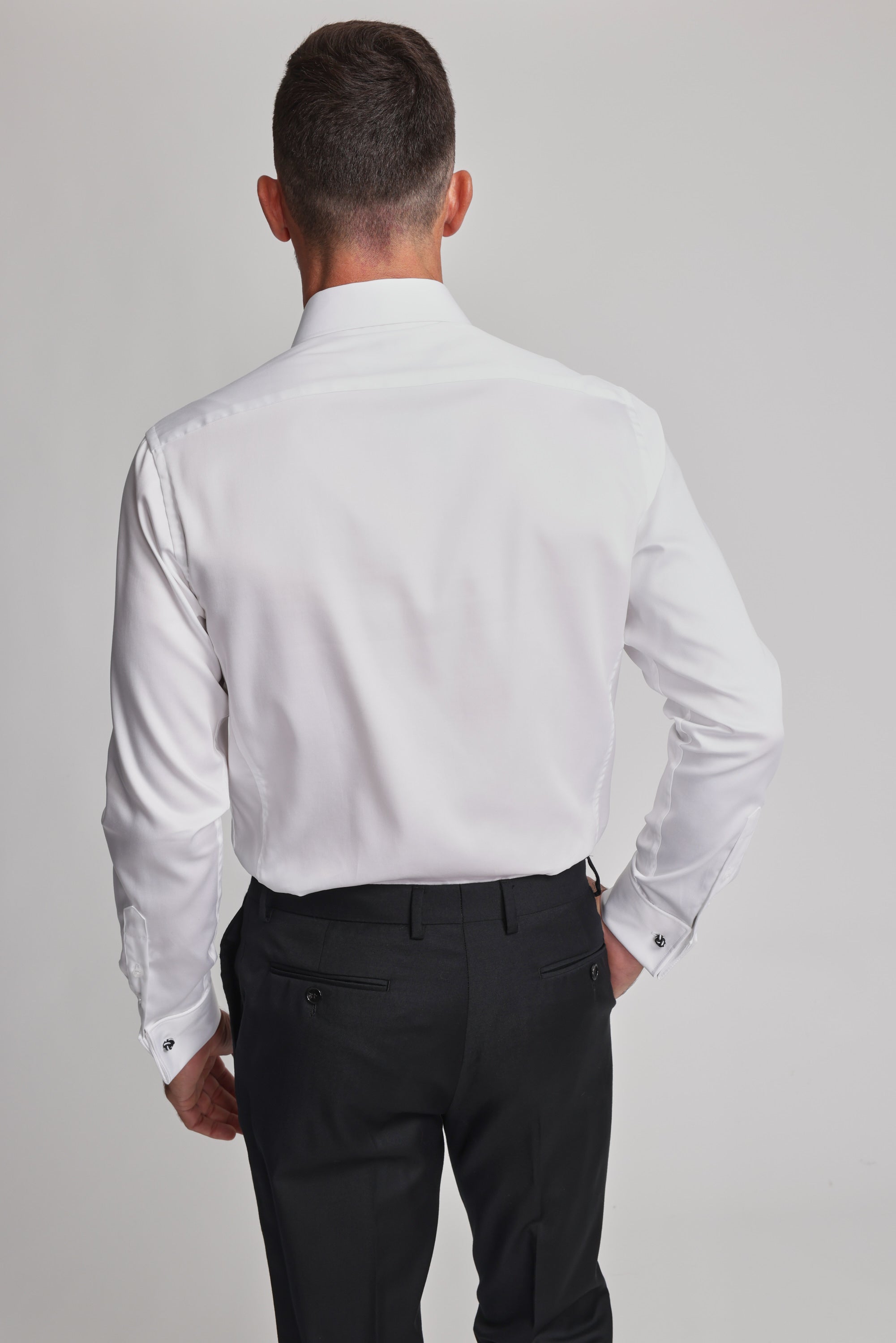 A man with short hair is seen from the back, wearing the Barkers Tribeca French Cuff Shirt and black dress pants against a plain, light-colored background.