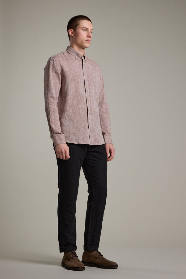 A man stands against a plain background, wearing the Barkers Dorset Linen Shirt in light pink with a tailored fit, paired with black pants and brown shoes. He faces left with a neutral expression, arms relaxed at his sides.
