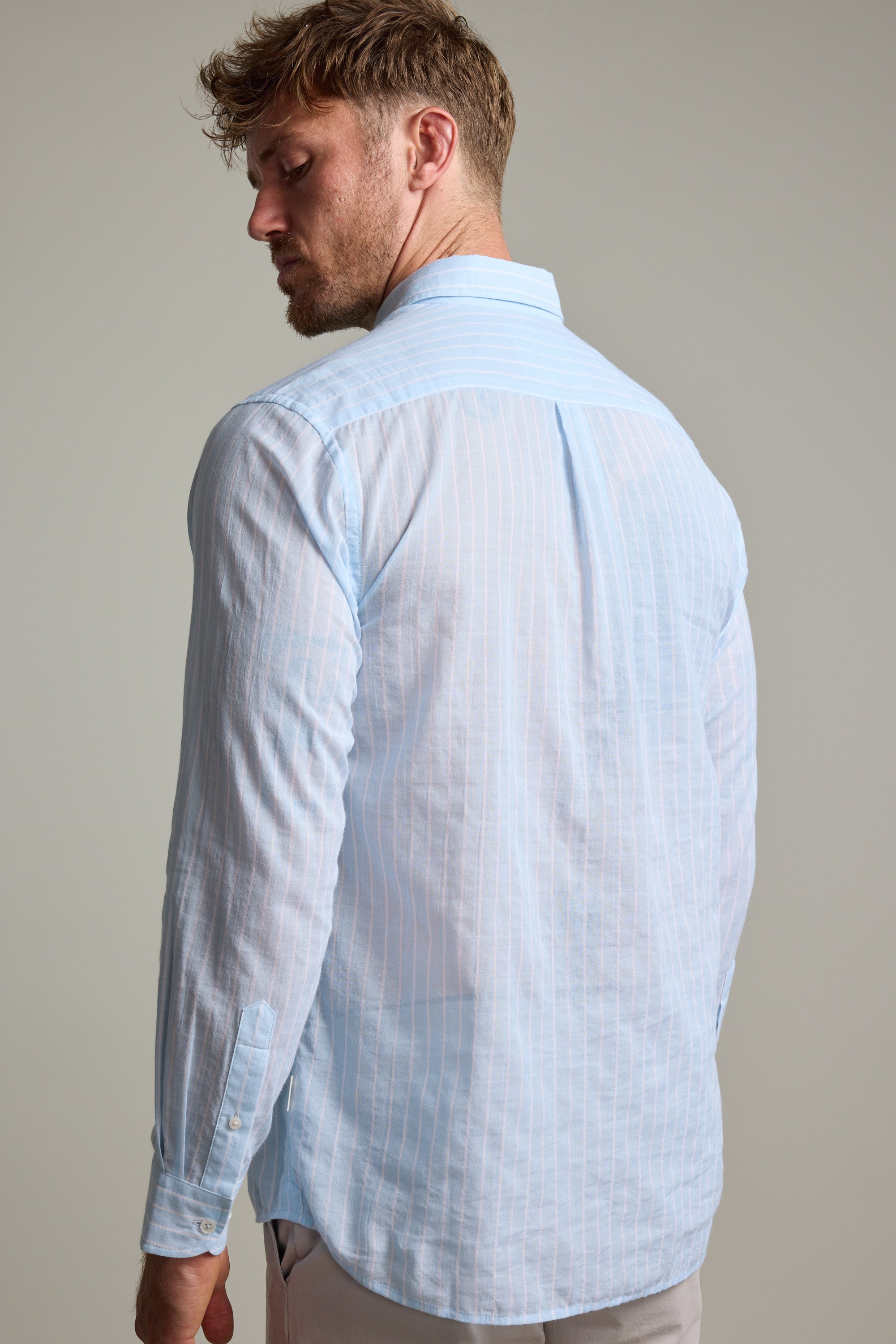 A man with short, light brown hair wears the Barkers Russell Stripe Shirt, a lightweight 100% cotton long sleeve featuring vertical white stripes, shown from the back against a plain background.