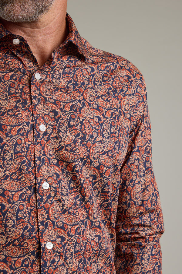 A close-up of a man’s torso wearing the Barkers Paisley Business Shirt in a classic fit, featuring vibrant red, orange, and blue patterns. Made with Eco Easy Care fabric; his face is partially visible with a short beard.