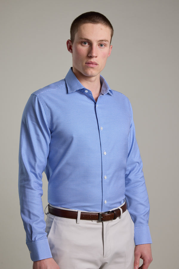 A man with short brown hair wears the Barkers Mitchel Check Business Shirt in light blue and beige pants, standing against a plain light gray background and looking directly at the camera with a neutral expression.