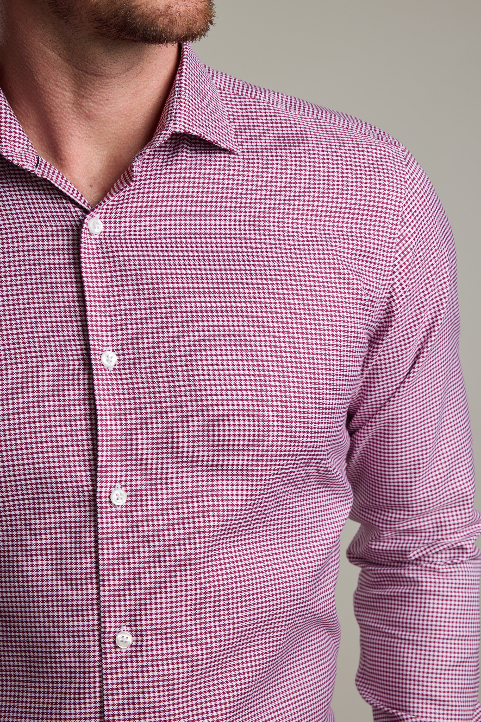 A close-up shows the lower face, neck, and upper torso of a person wearing Barkers' Mitchel Check Business Shirt—a tailored fit, long-sleeved shirt featuring a small red and white checkered pattern.