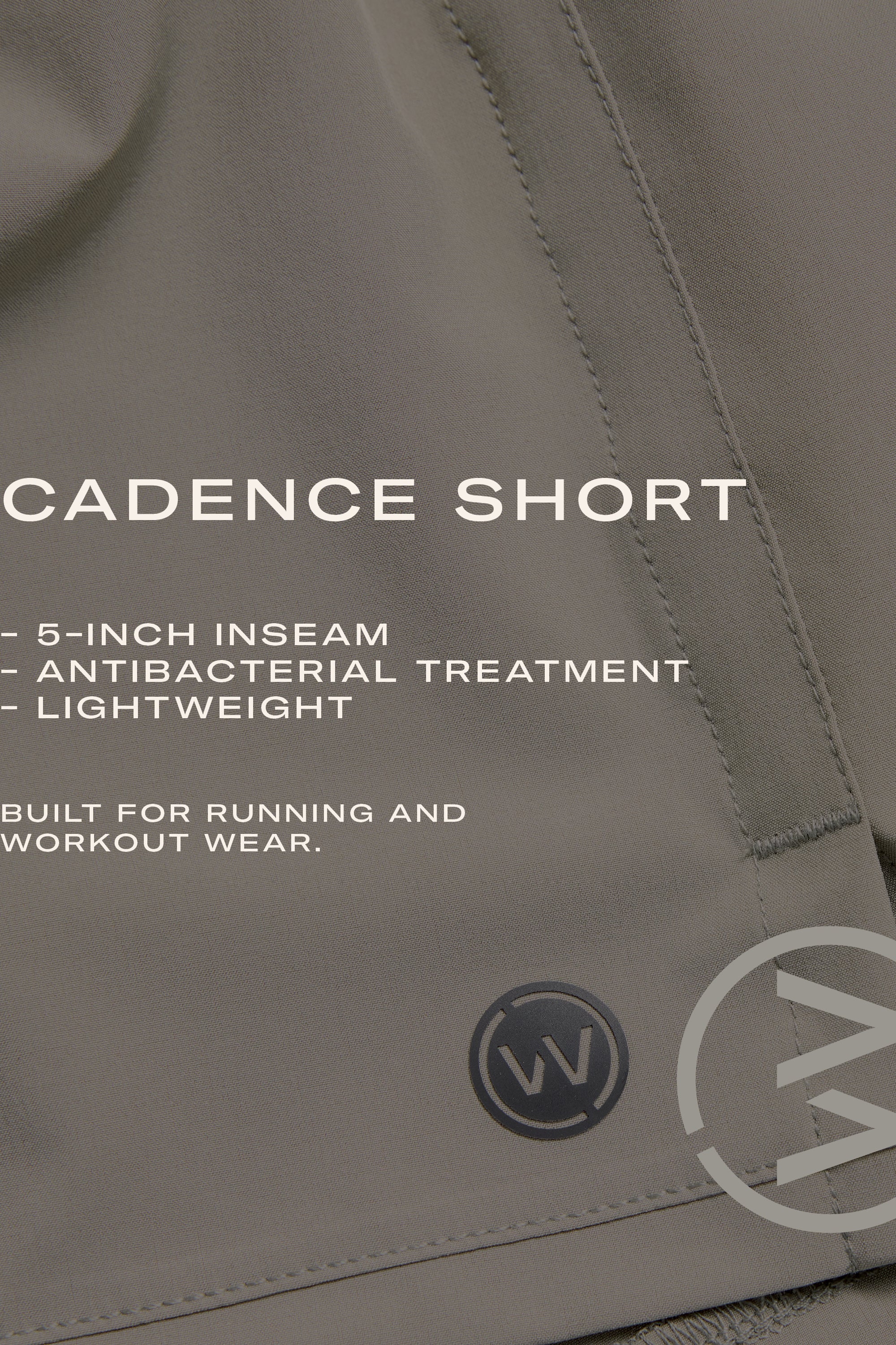 Close-up of gray WearEver Cadence Short with visible stitching. "5-inch inseam, lightweight breathable fabric, antibacterial finish. Designed for running and workouts." WearEver's circular logo shows at the hem.