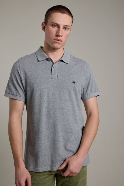 A young man with short hair wears the Barkers Regent Pique Polo in light grey and green pants, standing against a plain light background, looking directly at the camera with a neutral expression.