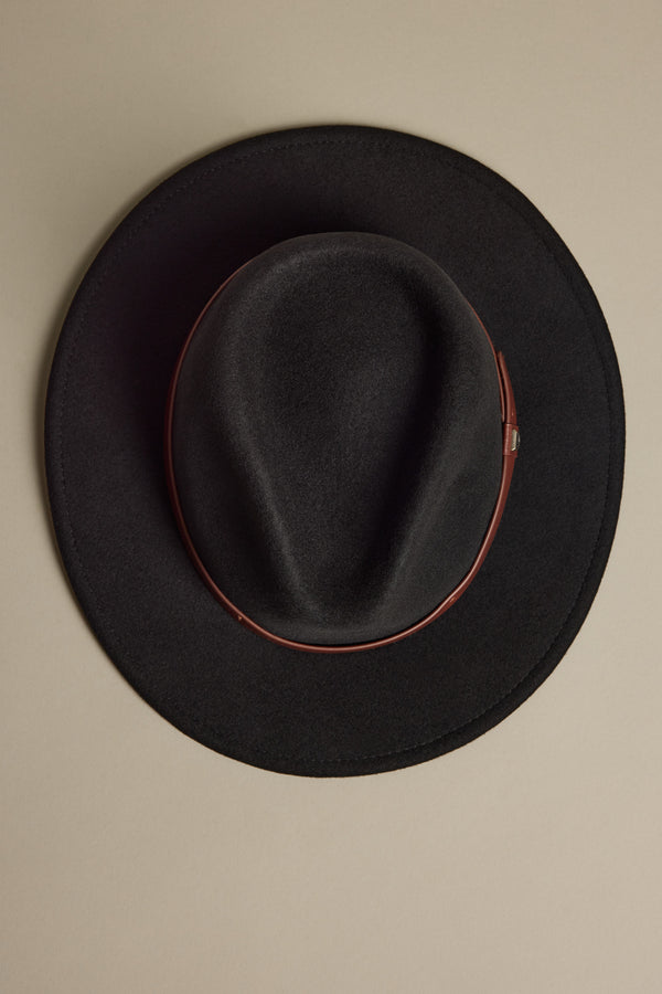 The Brixton Messer Fedora Hat by Brixton, featuring black wool felt and a brown leather band, is photographed from above on a beige background.