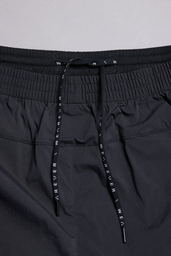 Close-up of the WearEver Agile Short's black elastic waistband, featuring gathered elastic and two black drawstrings with white "WEAR EVER" text from the WearEver brand.