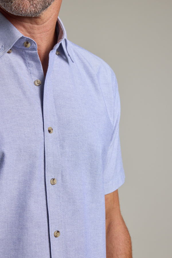 A man wears the Barkers Archer Oxford Shirt in light blue with a button-down collar.