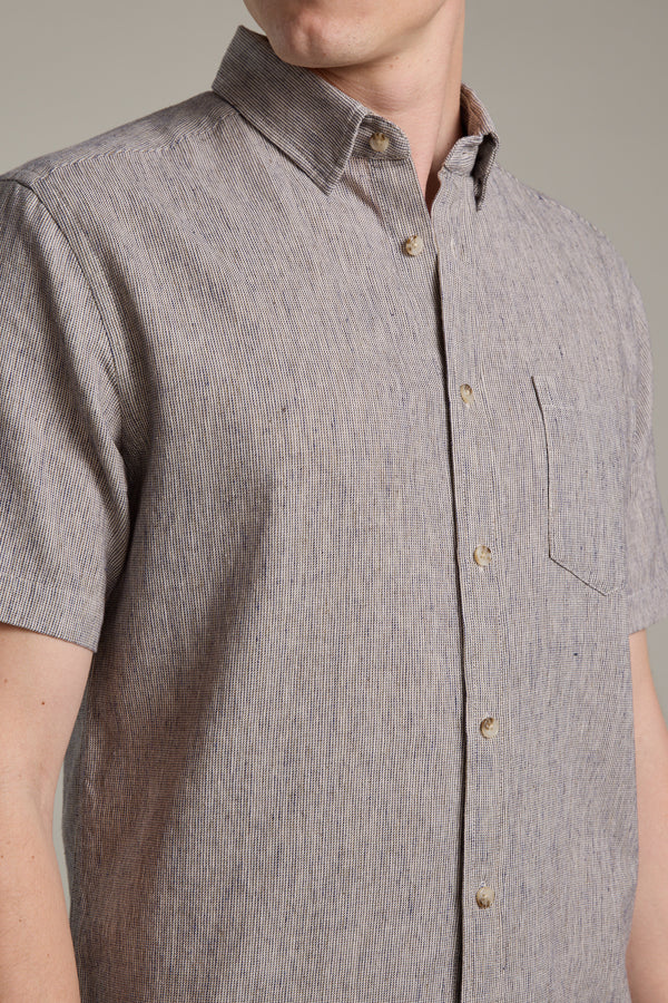 A person is seen from shoulders to waist wearing the Barkers Woodley Texture Shirt, a short-sleeved button-up featuring a subtle vertical stripe pattern and front pocket.