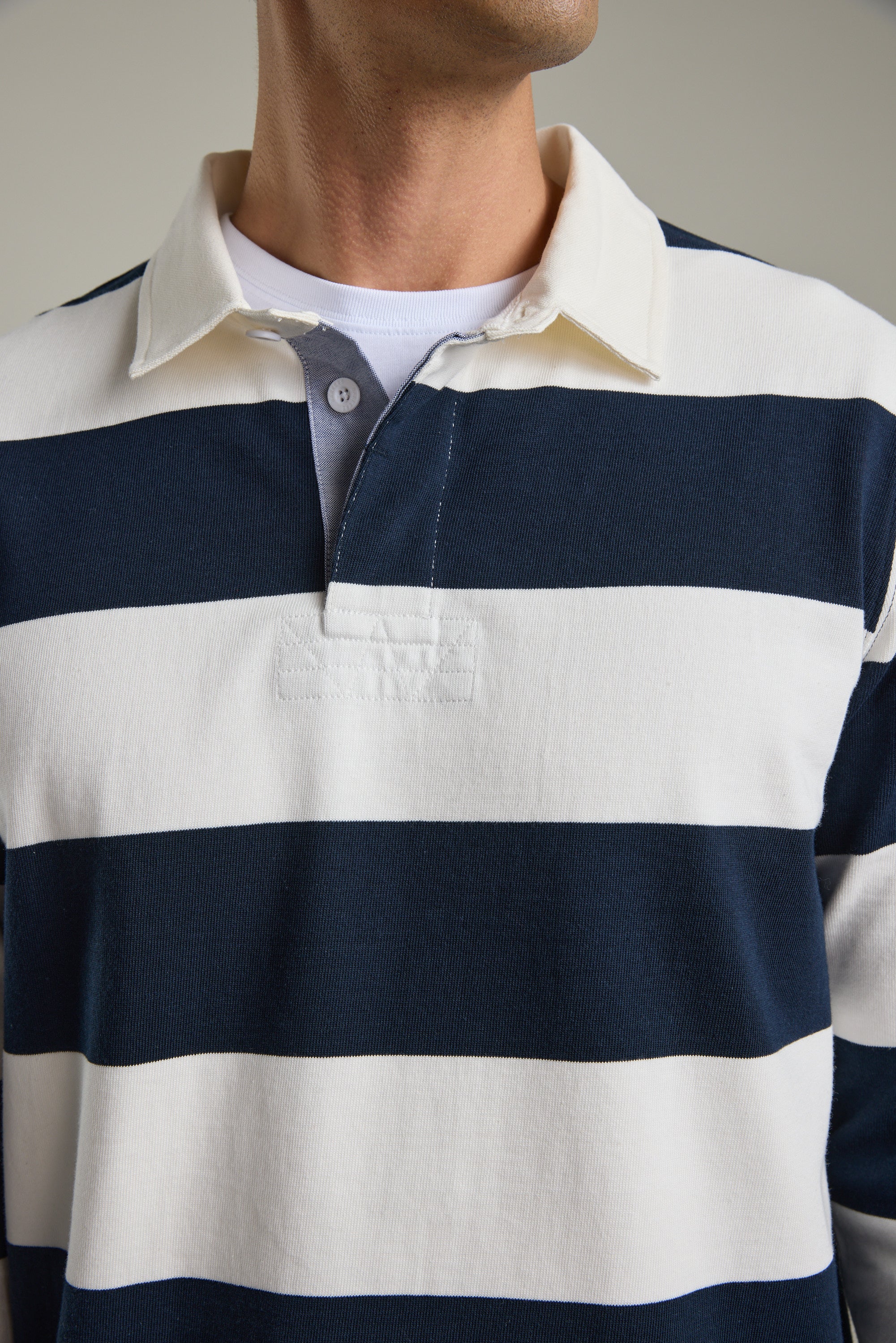 Wearing Barkers’ Provincial Long Sleeve Rugby Jersey in navy and white stripes with a white collar.