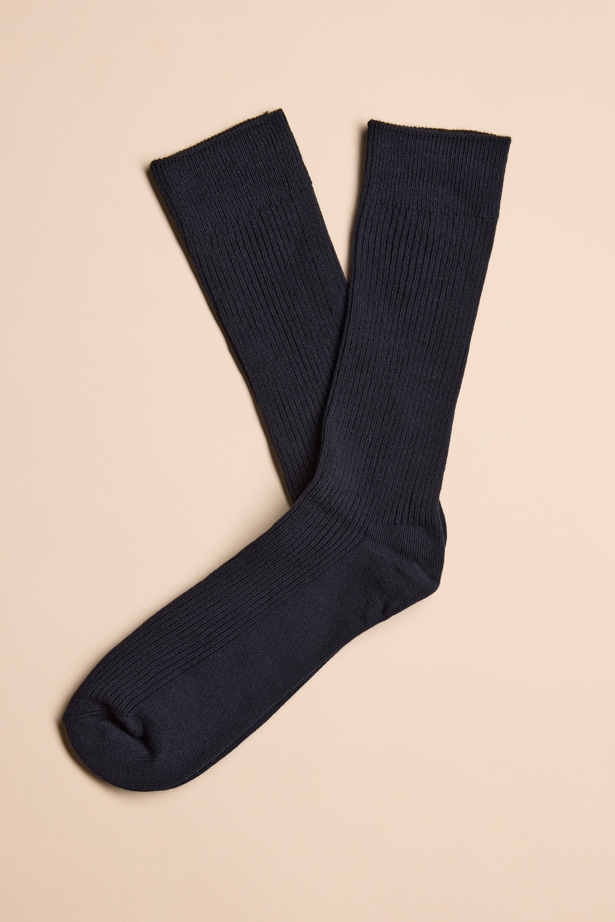A pair of Barkers Business Socks in black, crafted from responsibly sourced cotton, are laid flat on a beige surface with one sock slightly overlapping the other.