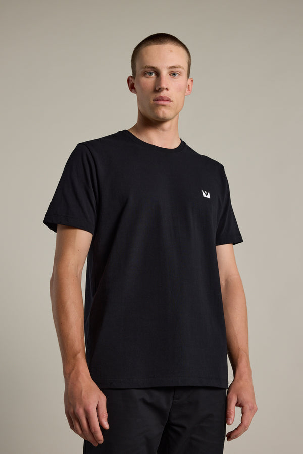 A young man with short hair wears the Barkers Newton Washed Tee in black, featuring an oversized box fit and a small white logo on the left chest, standing against a plain light background and looking straight at the camera.