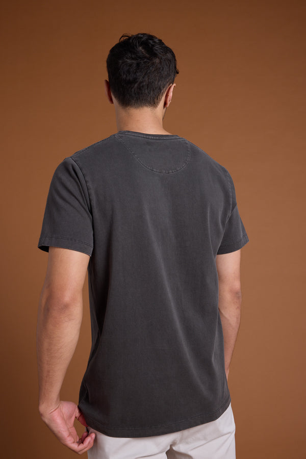 A man with short dark hair stands with his back to the camera, wearing the Barkers Newton Washed Tee and light-colored shorts against a plain brown background.