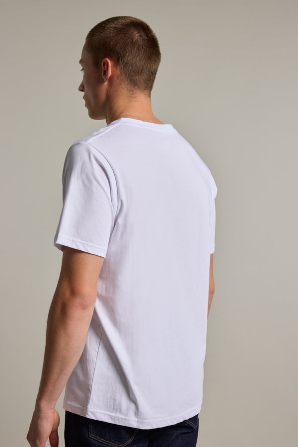 A young man with short hair stands with his back to the camera, wearing the Barkers Organic Cotton V Neck Tee in white and dark jeans, set against a neutral background.