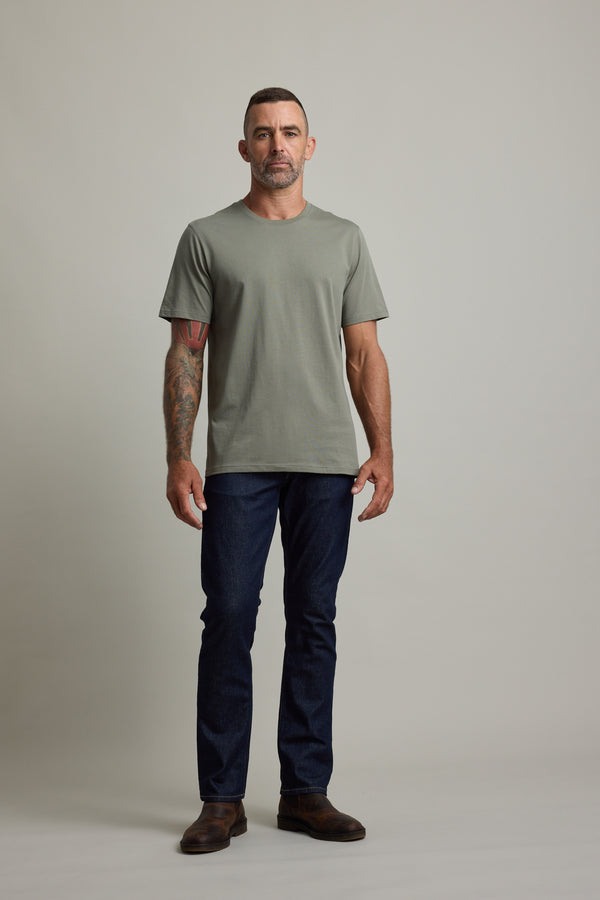 Man wears Barkers Good Earth Cotton Essential Tee in green against a neutral background.