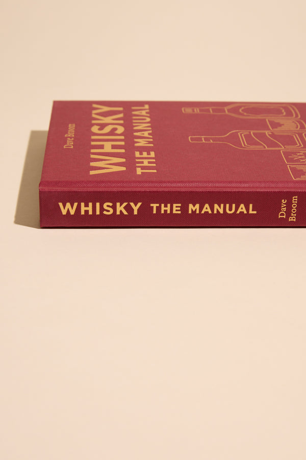 Whisky The Manual by Other rests on a beige surface; it’s a top whisky guide.