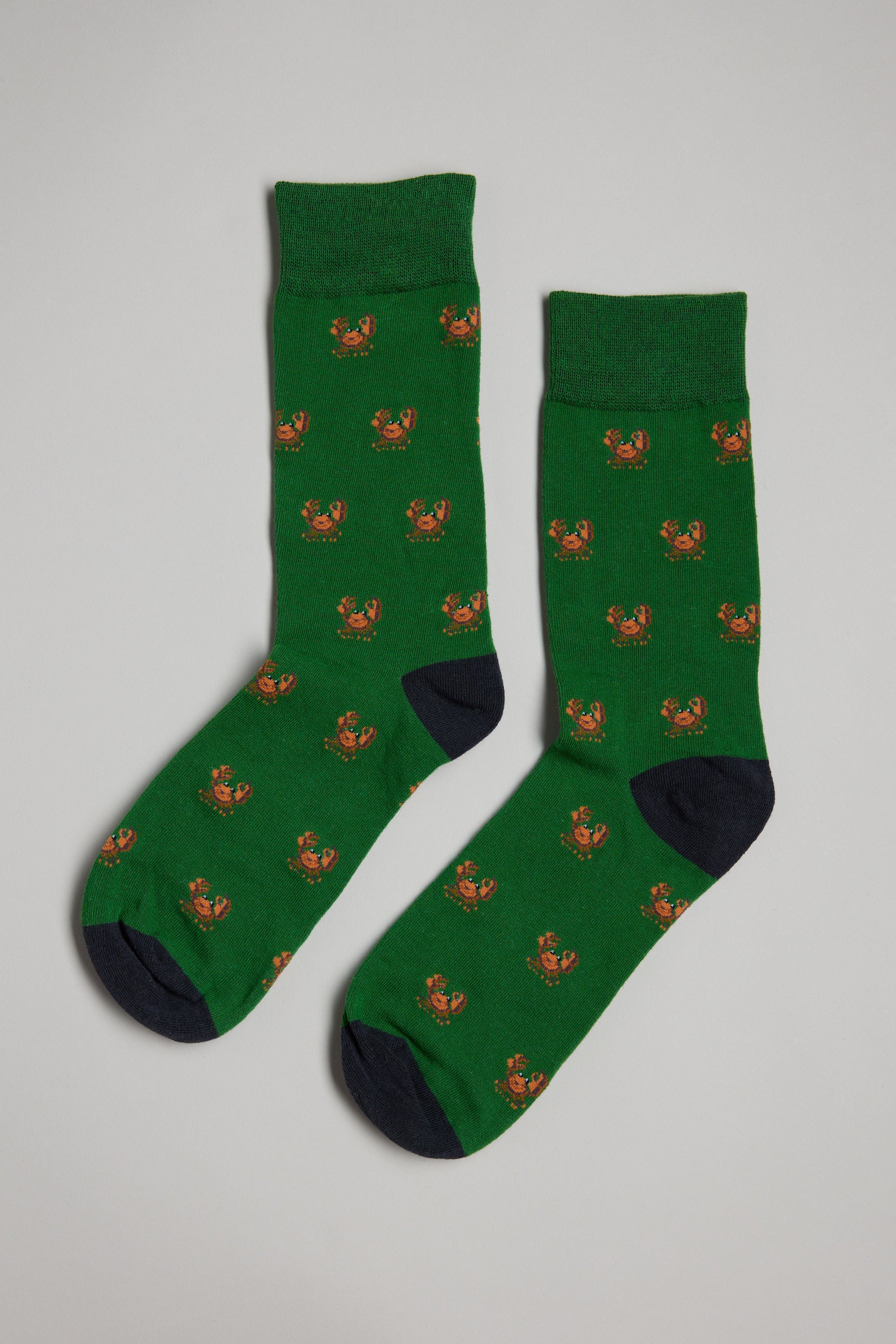 The Barkers Crab Sock is a green men's cotton sock with small orange crab patterns, black toes and heels—perfect as a gift—shown on a light gray background.