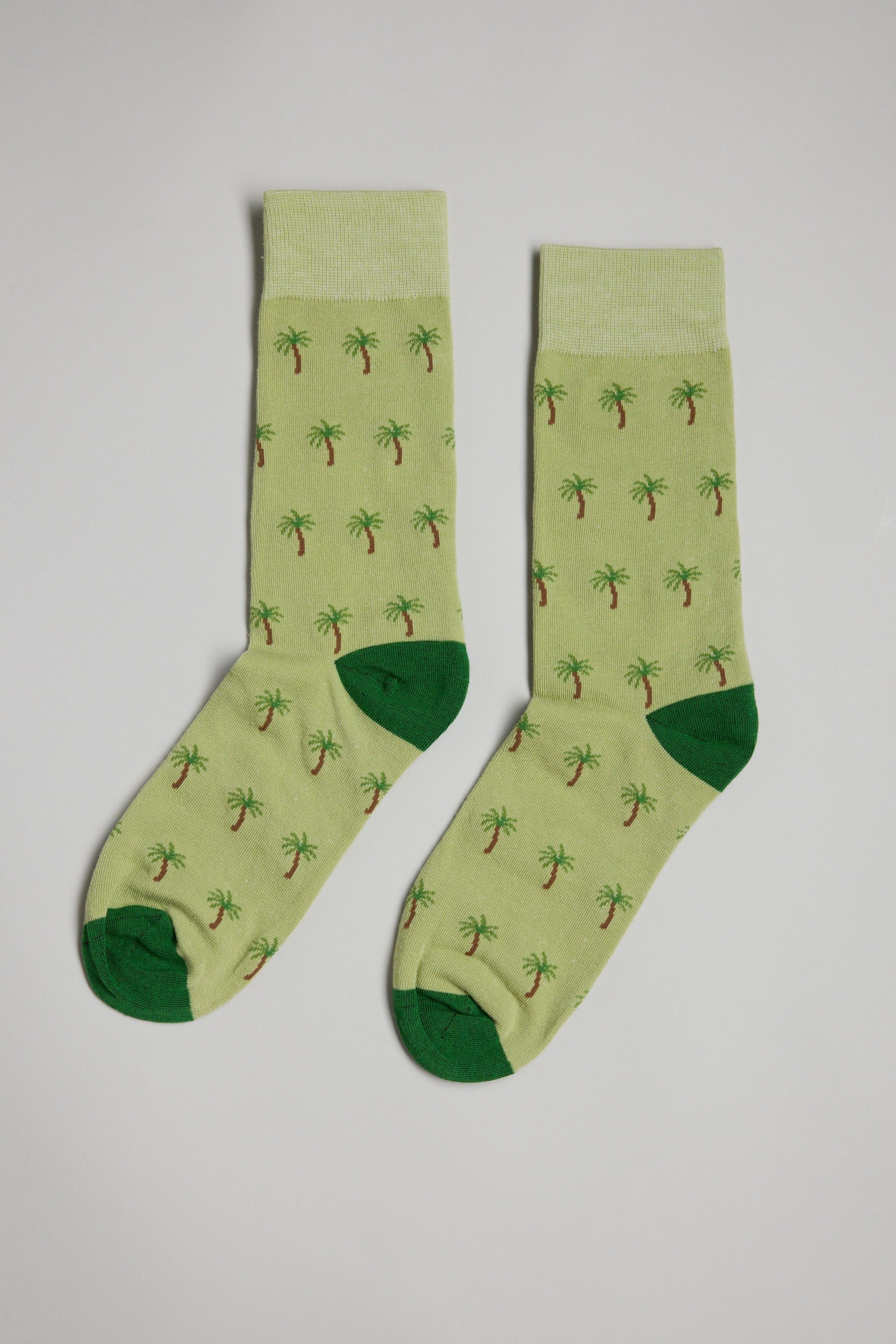 The Barkers Palm Tree Sock features light green fabric with dark green heels and toes, decorated with small palm tree patterns, shown on a plain white background.