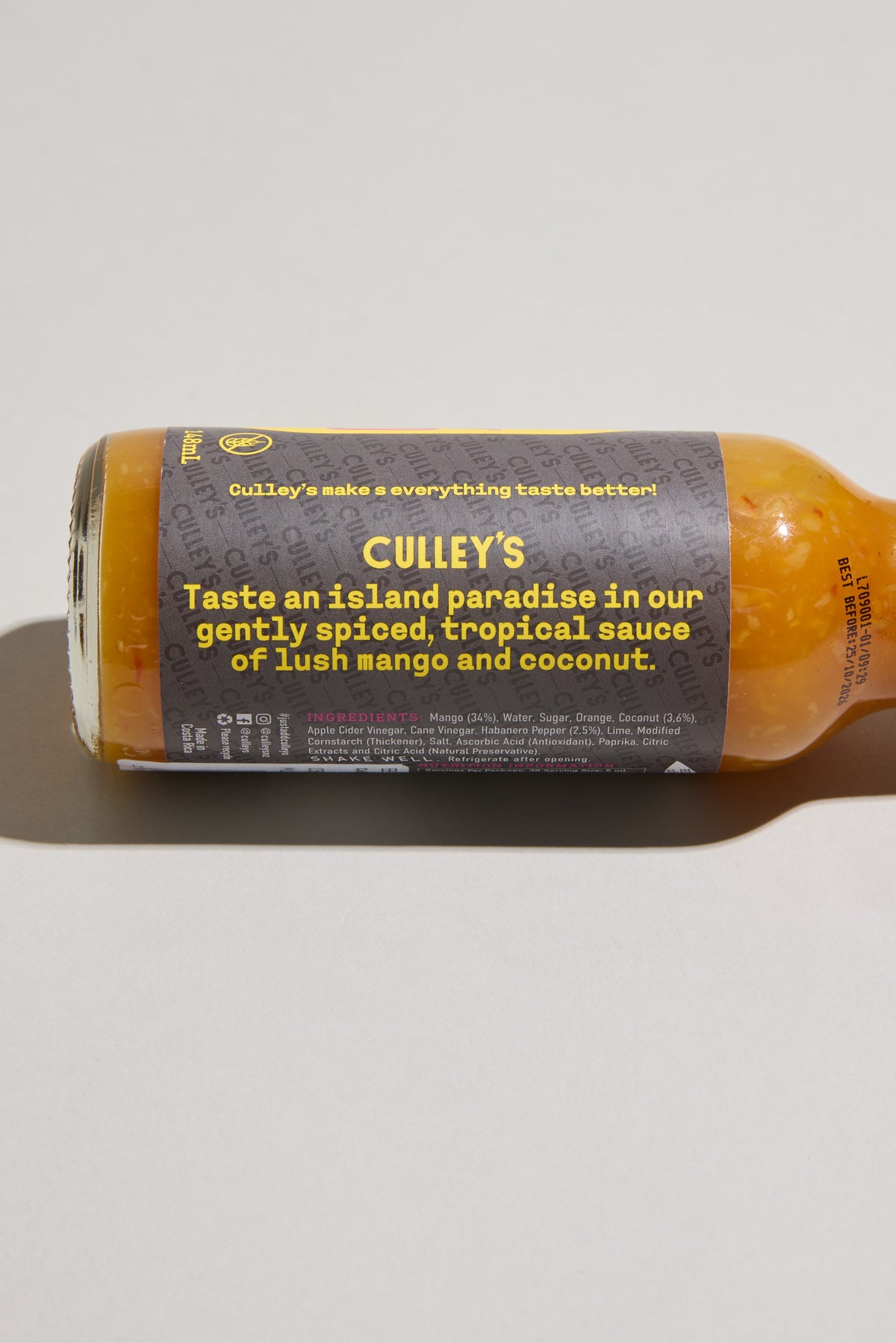 Culley’s Dreamy Mango-Coco Hot Sauce bottle lies on its side on a light surface.